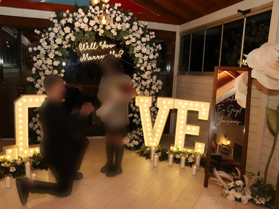 Işıklı LOVE harfleri önünde evlilik teklifi